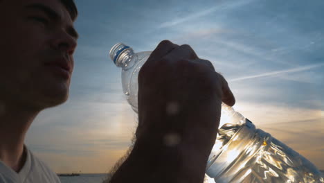 man drinking fresh water from the bottle at sunset