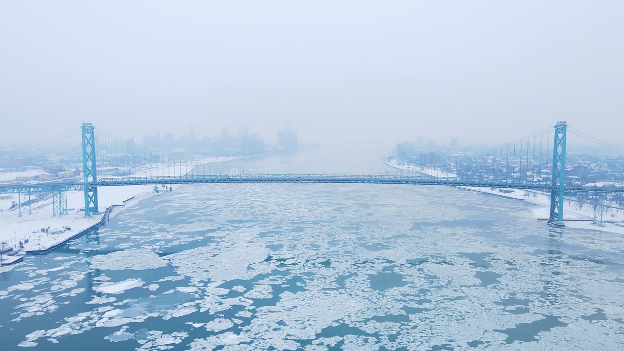 Drone video of Ambassador Bridge stretching across icy Detroit River under overcast winter skies