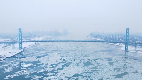 drone video of ambassador bridge stretching across icy detroit river under overcast winter skies