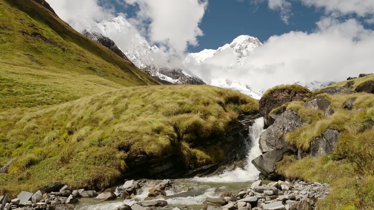 Waterfall Stream and Himalayas Mountains in Nepal, Snowcapped Mountain Top Landscape and Flowing River Scenery in High Altitude Terrain in Annapurna Region at Annapurna Base Camp