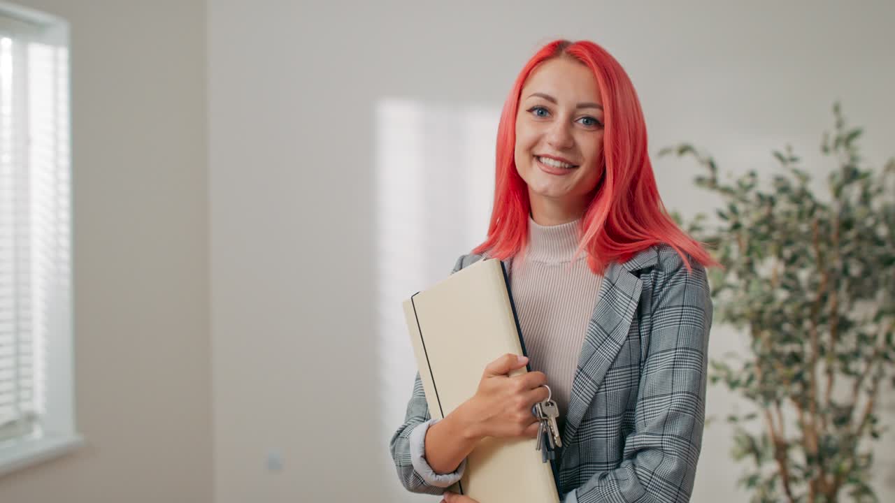 una mujer de cabello rosa se encuentra contra una pared blanca en una habitación vacía, una chica sostiene una carpeta con documentos en sus manos, un contrato de compra, alquiler de apartamento agente de bienes raíces asegurador inquilino de la casa