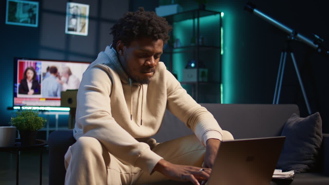 African american male freelancer managing creative projects remotely in his loft, working on a new novel or script for his gig. Man focusing on writing and editing creation, telework. Camera B.