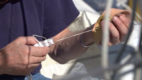 hombre cosiendo, reparando una vela