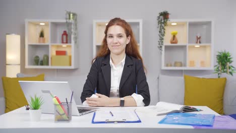 una trabajadora de oficina en casa mirando a la cámara con complacencia.