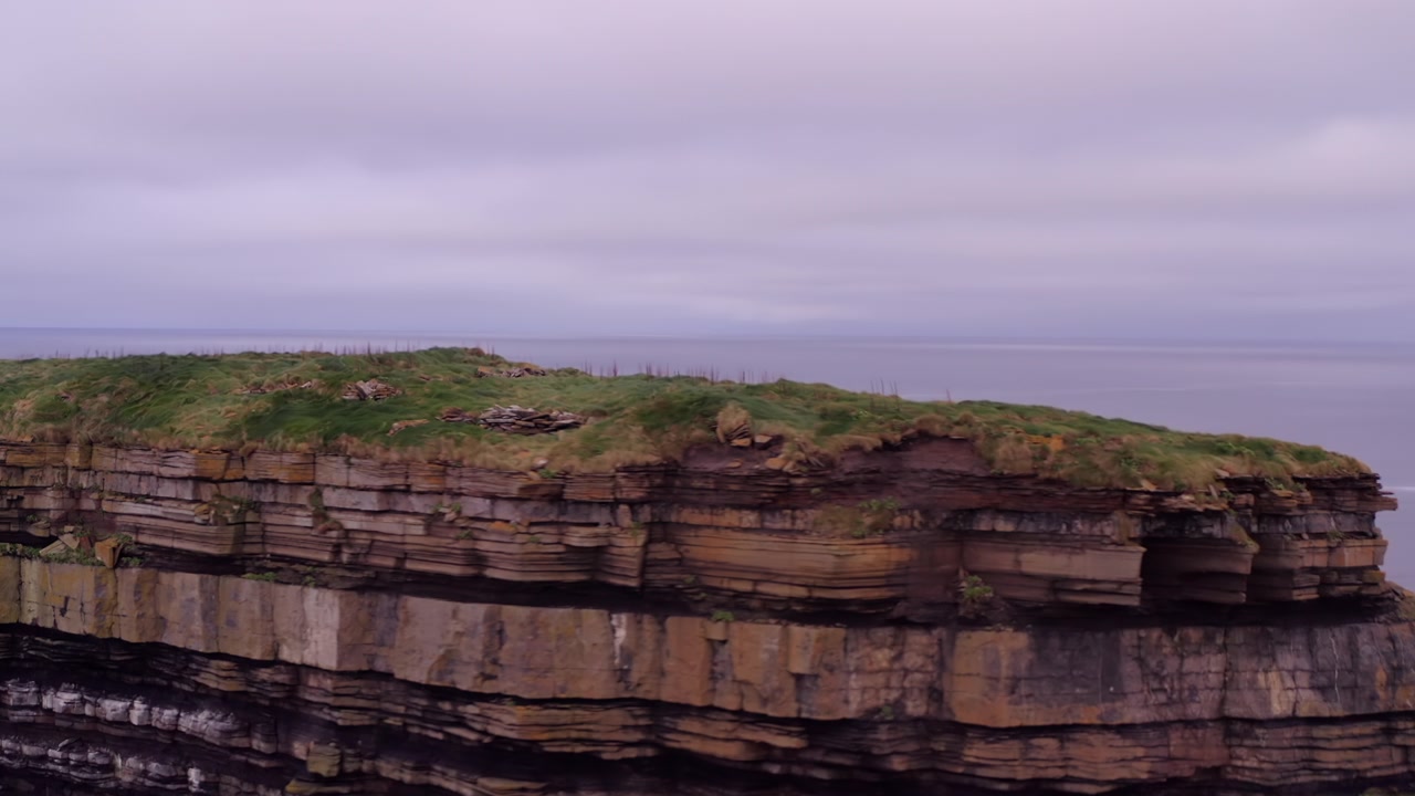 Medium telephoto aerial orbit and pullback from layered stacked rocks of Dun Briste sea stack at Downpatrick Head Ireland