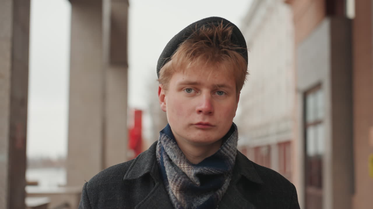 Poet dressed for city walks pauses. Calm writer standing outside in cold weather environment. Caucasian author quietly contemplating in outdoor setting during chilly weather conditions