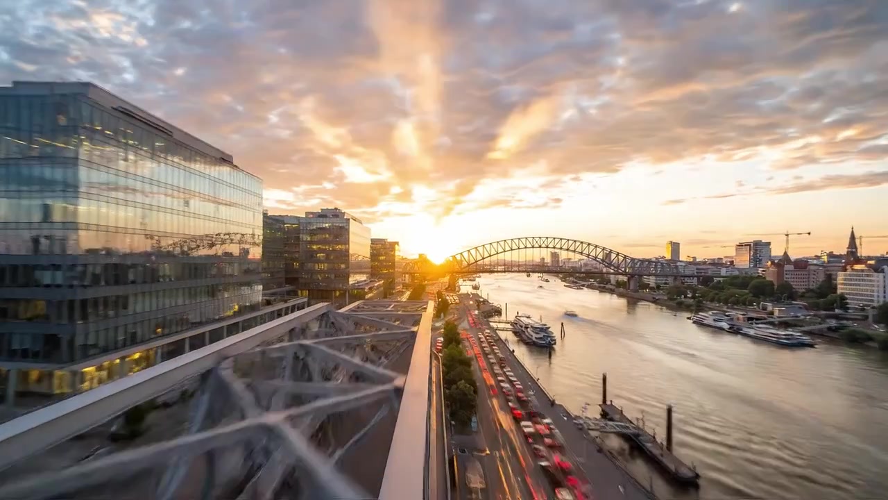 Scenic Urban Evening: Captivating Cityscape Overlooking River, Bridge, and Modern Architecture at Sunset with Cloudy Sky and Reflective Water in Twilight Glow