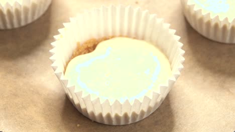 cupcake pan is filled by pastry chef in close-up view of cookie pan