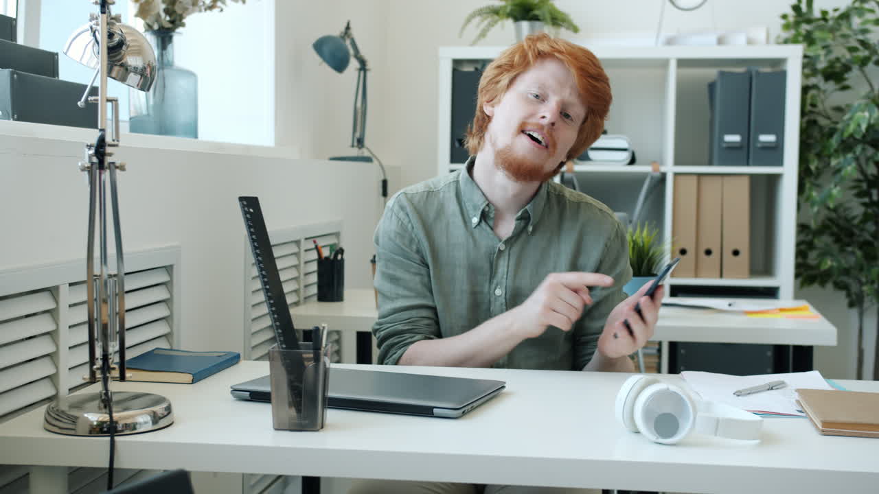 Uomo che mostra uno smartphone in un ufficio moderno.