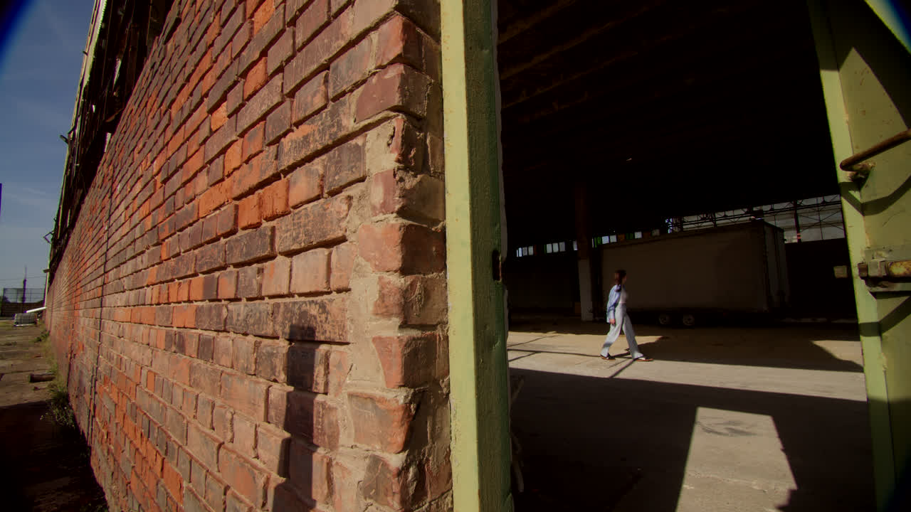 Woman walking through a gate of an abandoned industrial building