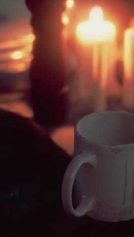 a white mug on a table with candles in the background