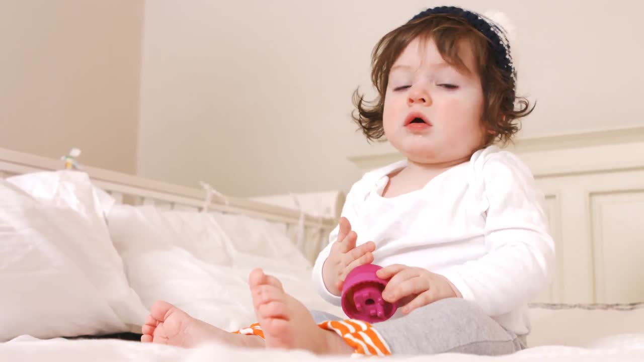 침대에 앉아 있는 귀여운 아기 소녀