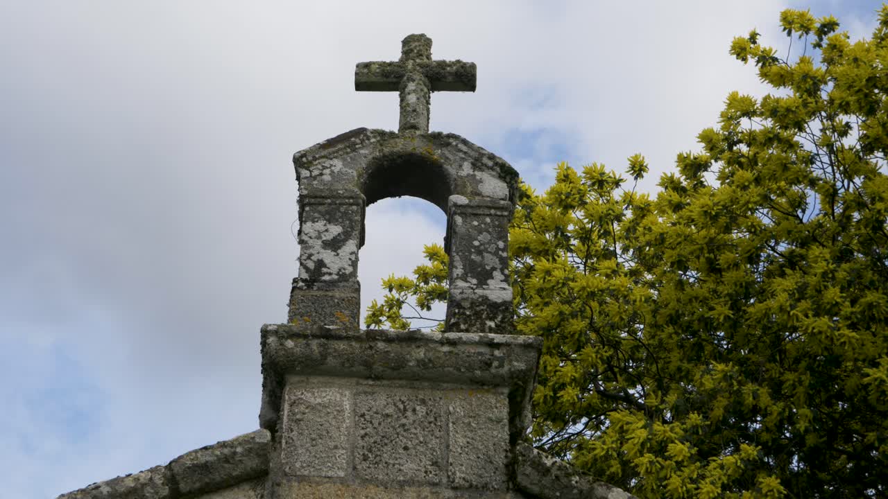 низкий угол взгляда на вырезанный каменный крест и мох лишайники и желто-зеленые цветы в часовне сан-витоиро