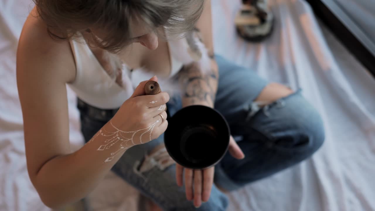 mujer con chakra limpiando el cuenco de canto tibetano en casa