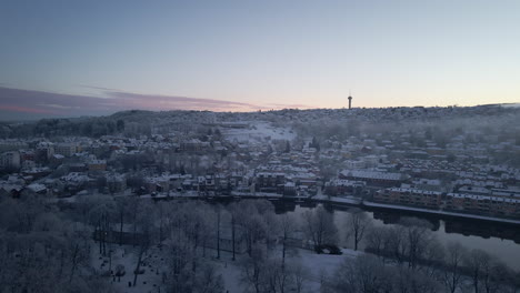 aerial view of trondheim city covered with fresh snow with tyholt tower in the distance at winter in norway