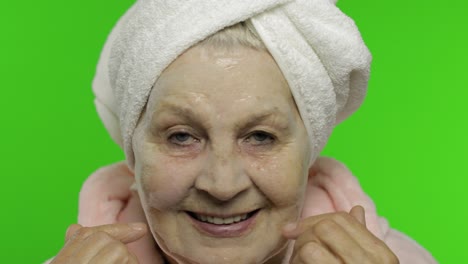 abuela anciana después de la ducha. anciana aplicando máscara facial de burbujas cosméticas
