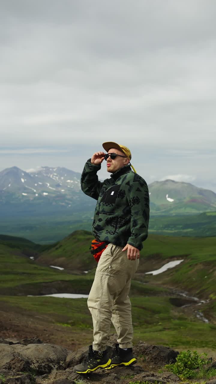 Uomo in piedi sulla cima di una montagna che ammira un paesaggio suggestivo.