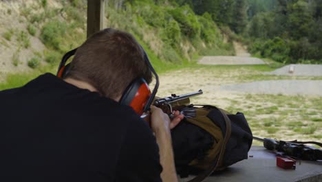 man firing shotgun at an outdoor firing range