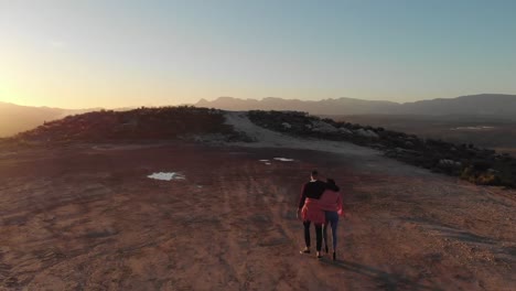 pareja joven en un viaje por carretera caminando a la cima de la montaña al anochecer