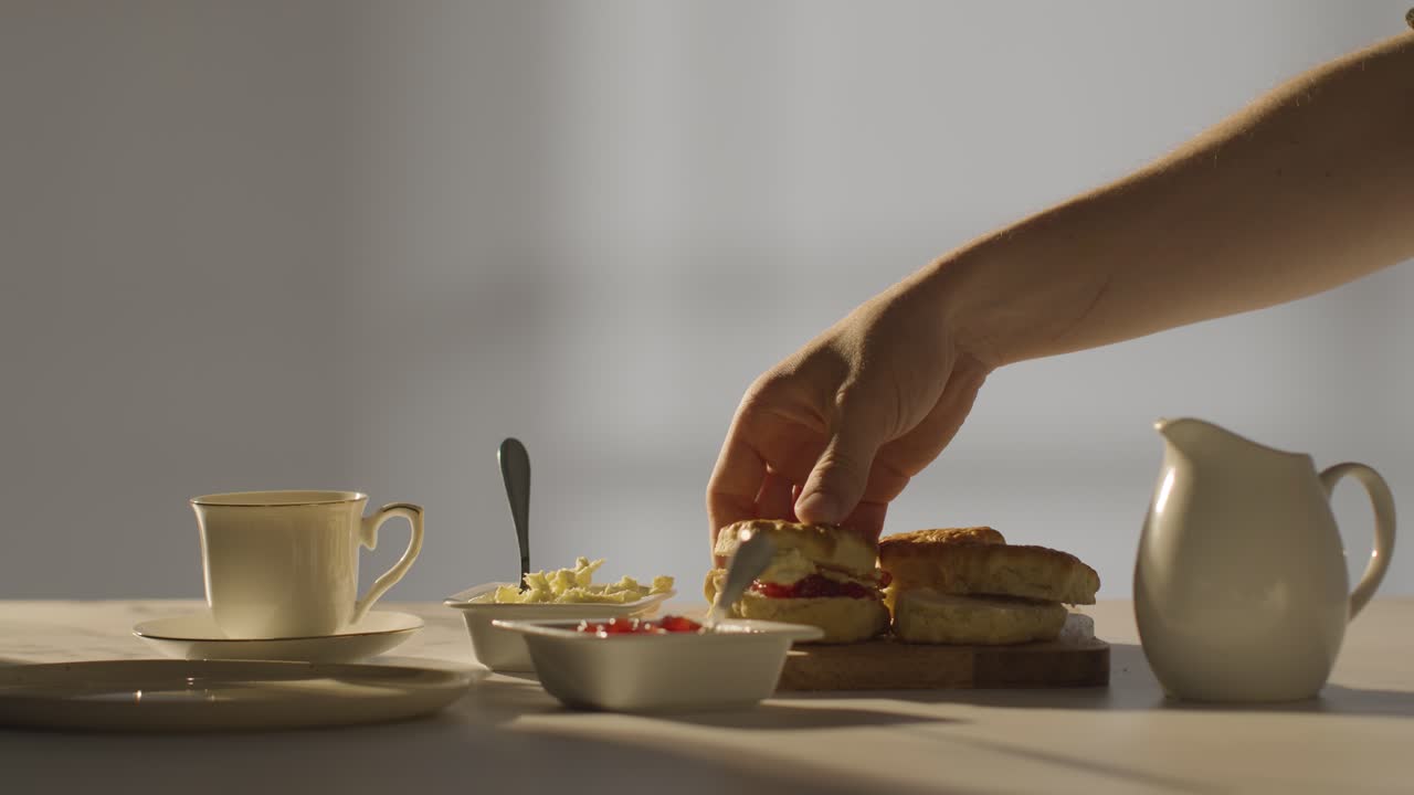 fotografía de estudio de una persona con el tradicional té de la tarde británico con crema de bollos y mermelada 3
