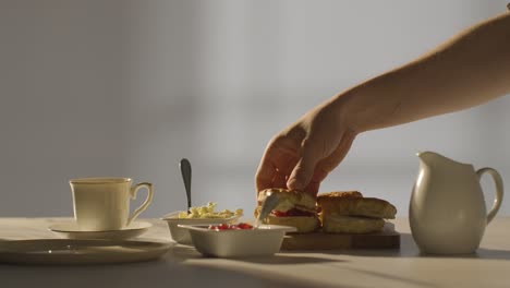 Studio-Shot-Of-Person-With-Traditional-British-Afternoon-Tea-With-Scones-Cream-And-Jam-3