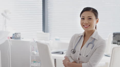 portrait of smiling female doctor with stethoscope standing by desk in office