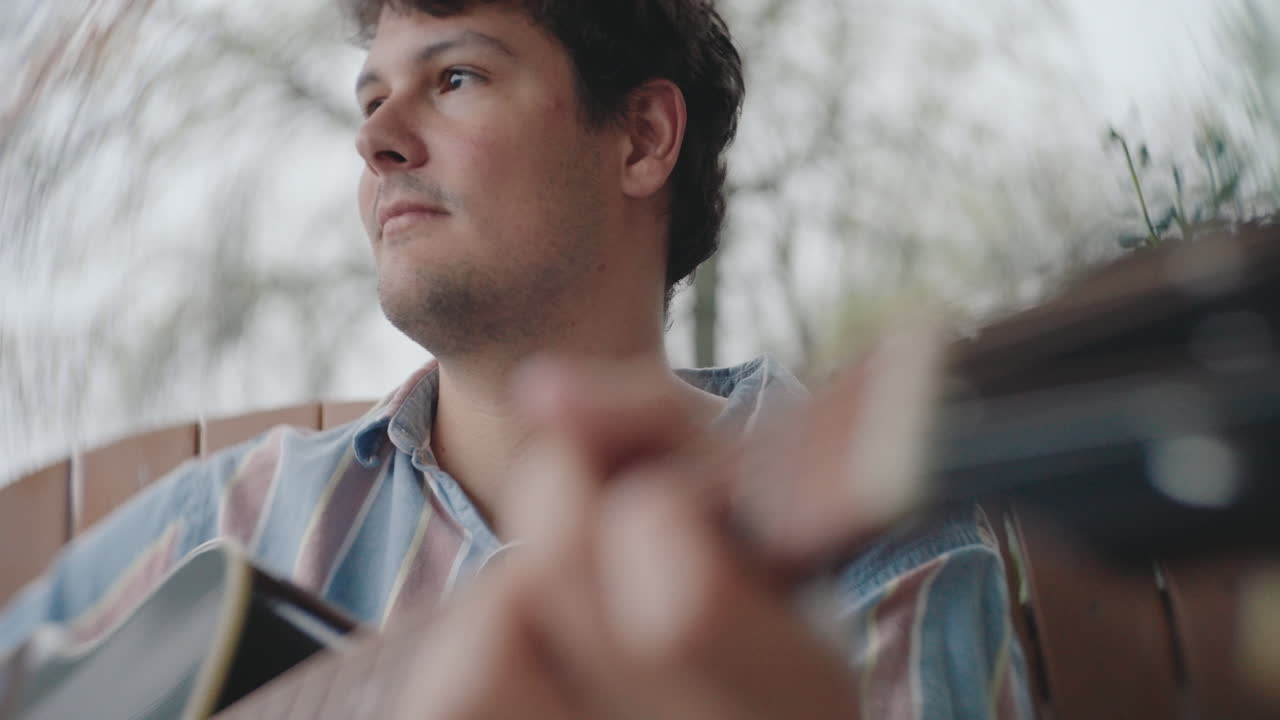 야외에서 어쿠스틱 기타를 연주하는 남자