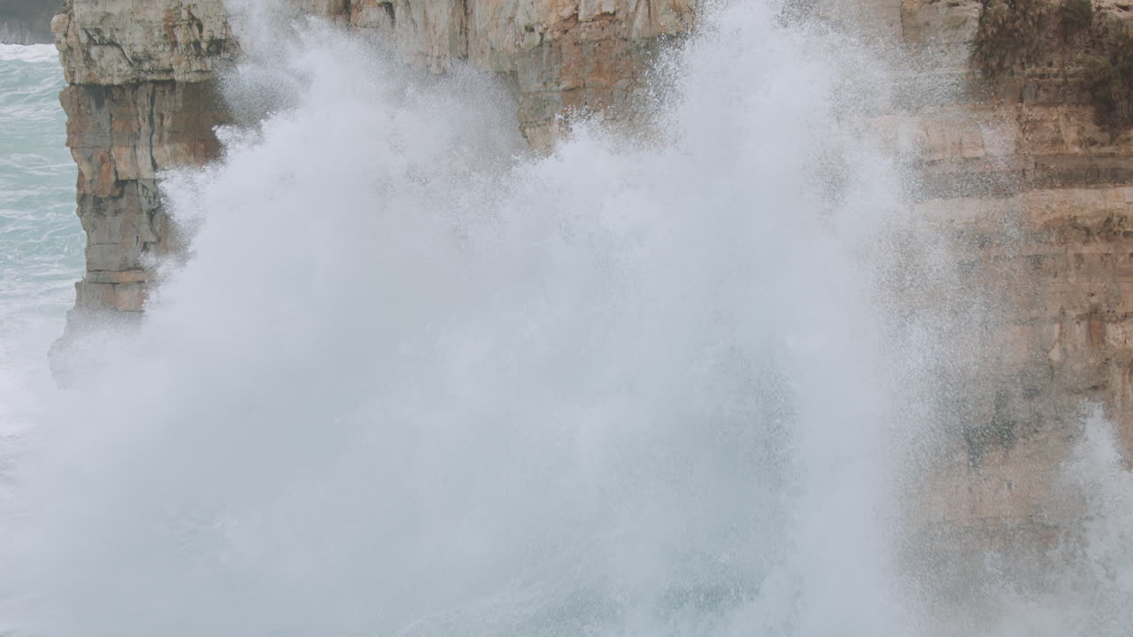 Waves crashing on the cliffs of Polignano a Mare during a storm in Adriatic Sea. Slowmotion 4k 120fps - tilt up