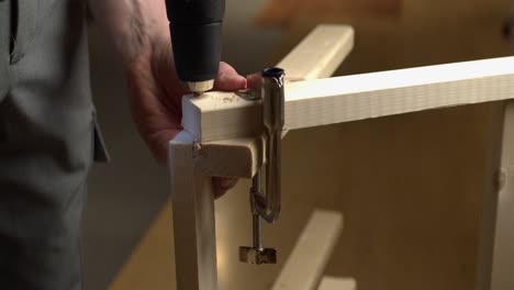 DIY-handyman-drills-hole-to-assemble-pine-lumber-construction-project