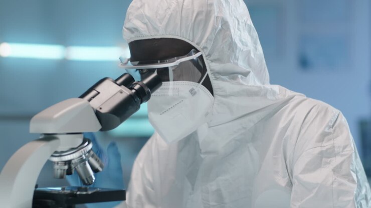 Scienziato afroamericano in tuta protettiva che usa un microscopio
