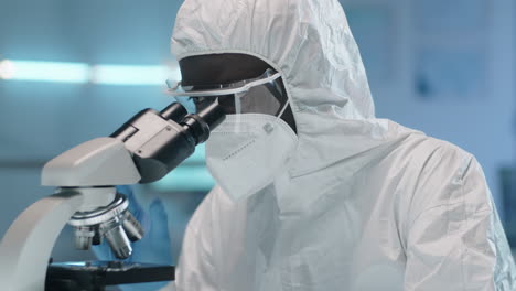 African-American-Scientist-in-Protective-Suit-Using-Microscope