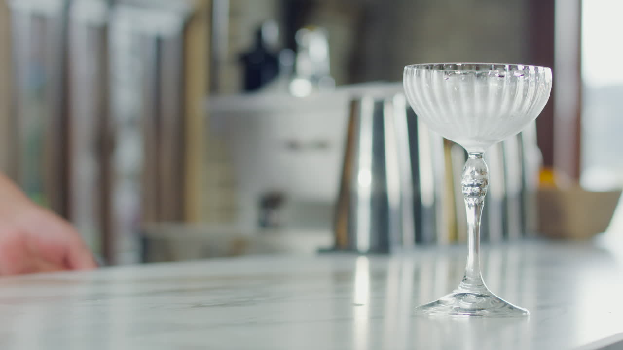 Close-up of a cocktail falling from a glass with ice into a crystal glass at a bar
