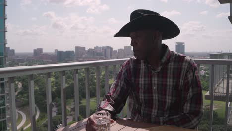 black man with cowboy hat looking over balcony with thinking