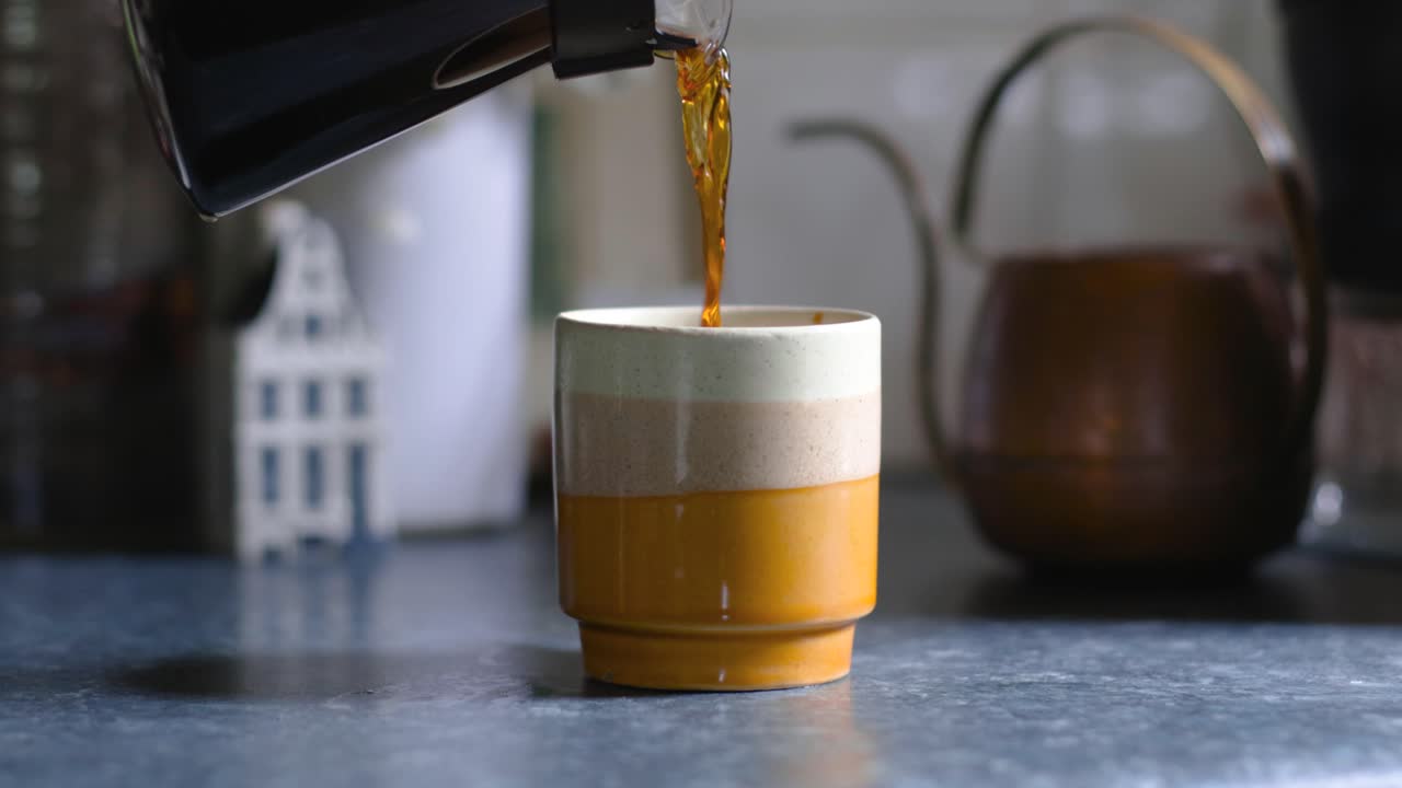 servidor de café vertiendo café en una taza pequeña