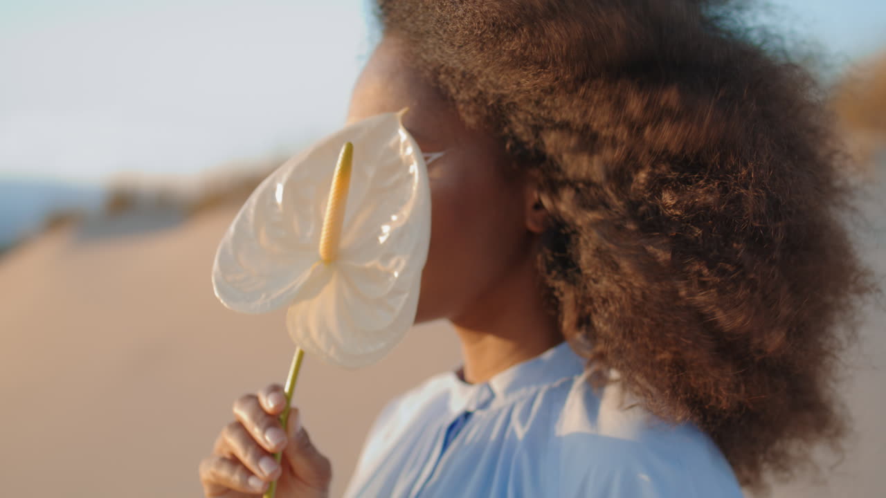 Gros plan d'un mannequin tenant une fleur dans un désert estival. Femme posant avec un arum.