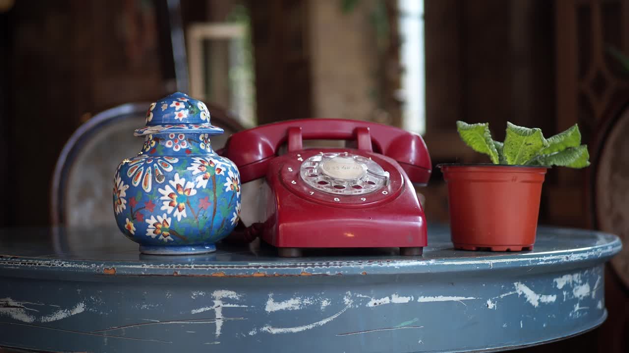 teléfono vintage y jarrón en una mesa azul