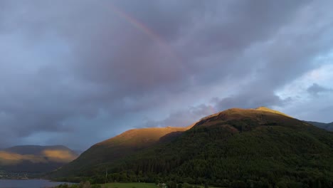 4k aerial drone footage of rainbow at sunset above mountains in scottish highlands scotland