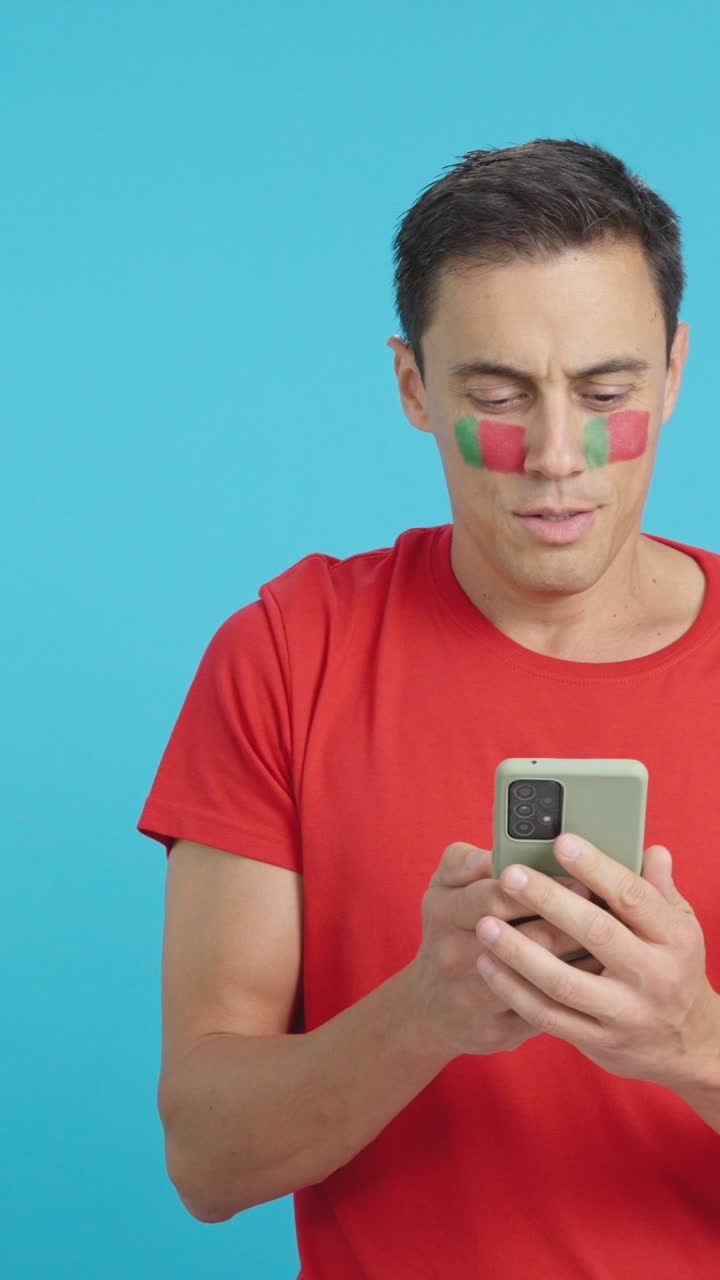 Portuguese supporter looking at his mobile smiling and showing it