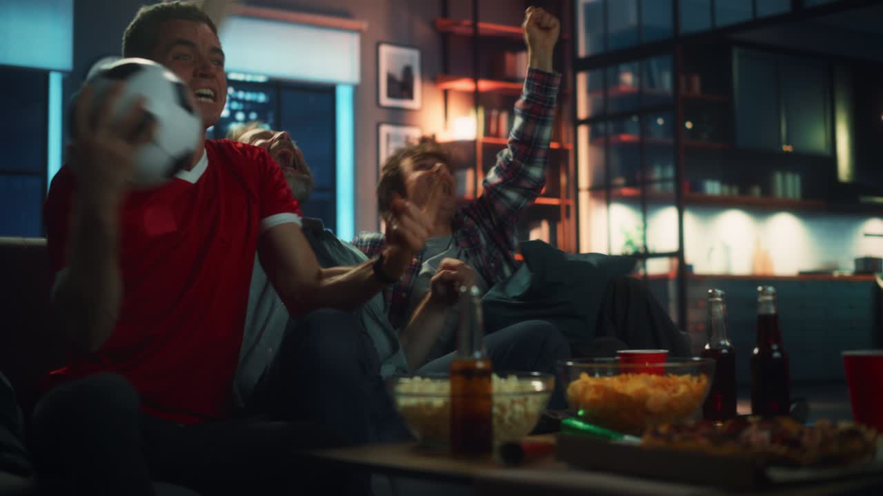 집에서 밤: 소파에 앉아있는 세 명의 축구 팬이 tv에서 경기를보고, 스마트폰 앱을 사용하여 온라인 베팅을하고, 스포츠 팀이 승리했을 때 승리를 축하합니다. 친구들이 환호합니다. 간식을 먹고, 축구 경기를 보십시오.