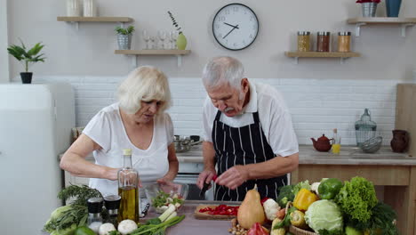 abuela y abuelo veganos mayores cocinando ensalada con verduras frescas en la cocina de casa