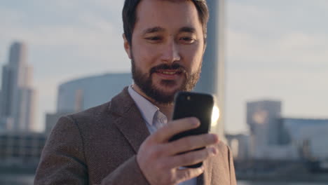 man using his smartphone on a terrace with blurred view of city buildings