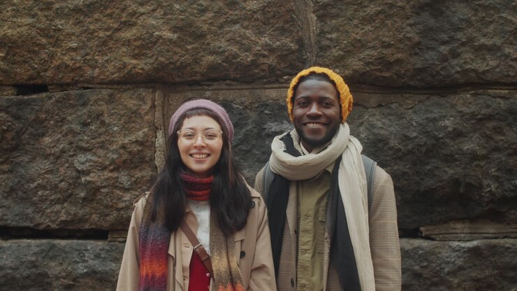 Portrait d'un couple multiethnique joyeux devant un vieux mur en pierre