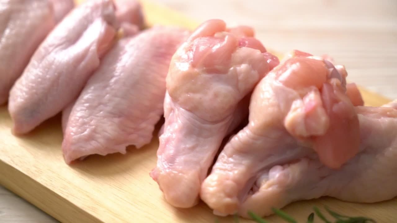 Alas de pollo crudo fresco sobre tabla de madera con ingredientes