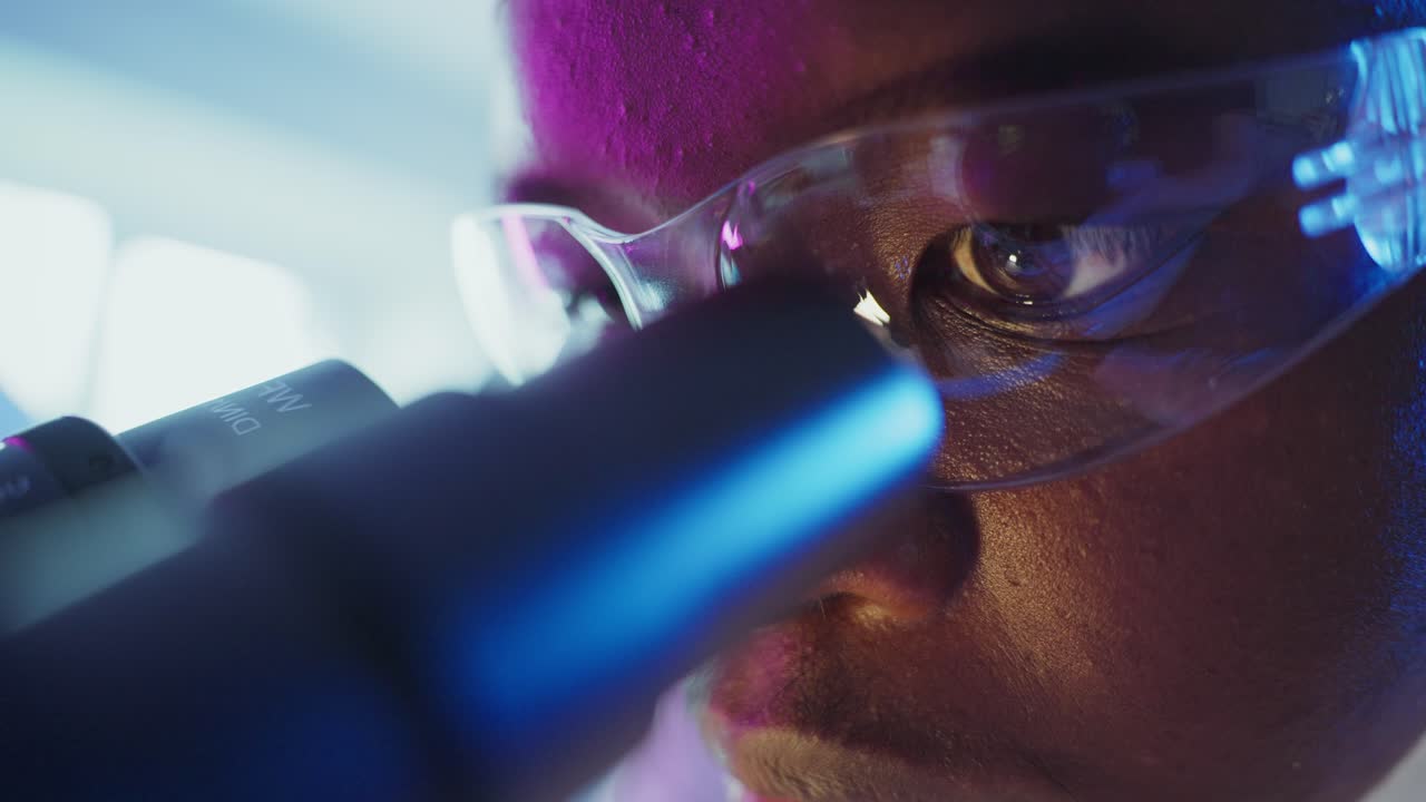 Forsker kigger i mikroskop i et laboratorium