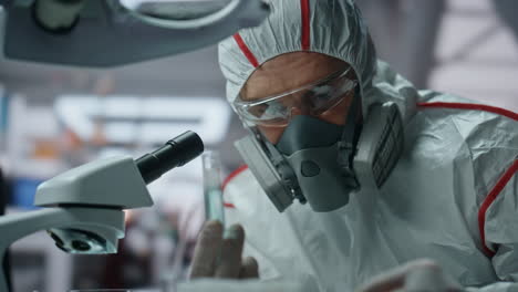 biochemistry specialist looking microscope in decontamination suit lab close up