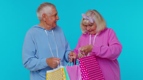 Senior-mature-grandparents-showing-shopping-bags,-advertising-low-price-discounts,-Black-Friday-sale