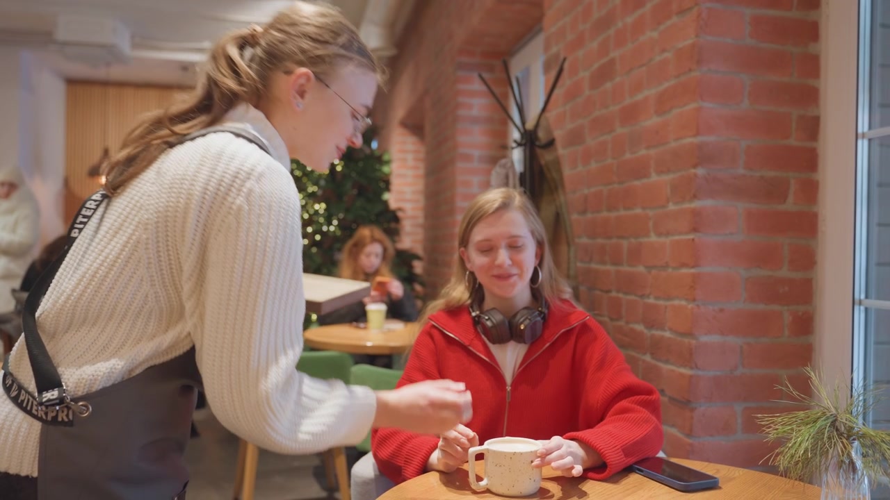 Giovane cameriera che serve caffè a una cliente in un bar