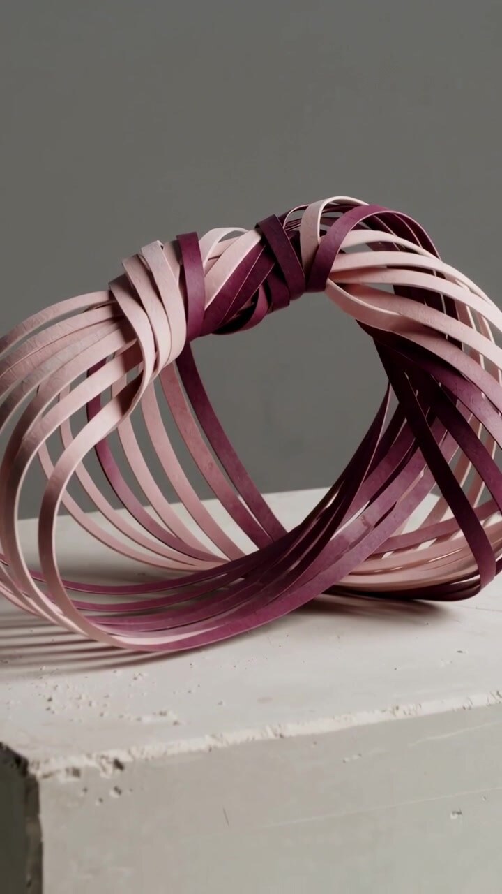 Vertical video: Pulling back camera revealing woven loop sculpture on painted shelf, exposing void