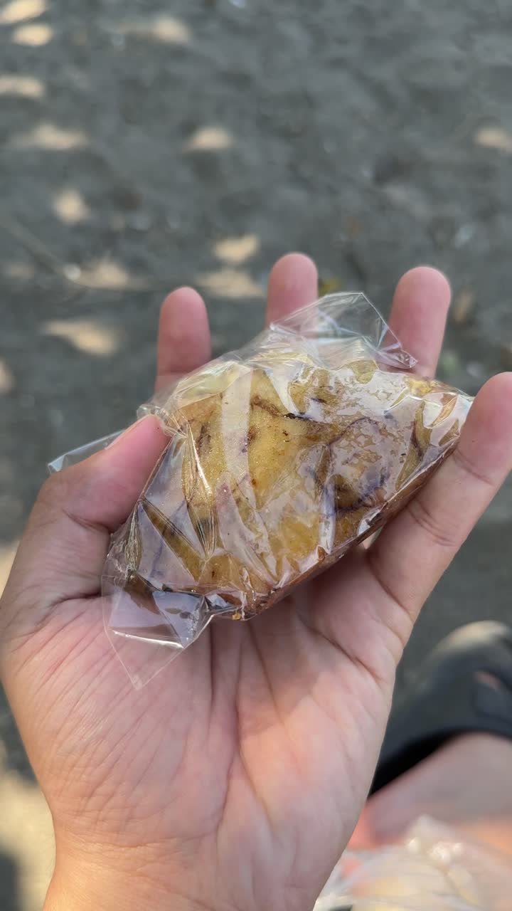 Mano che tiene uno snack fritto con peperoncino in un involucro di plastica