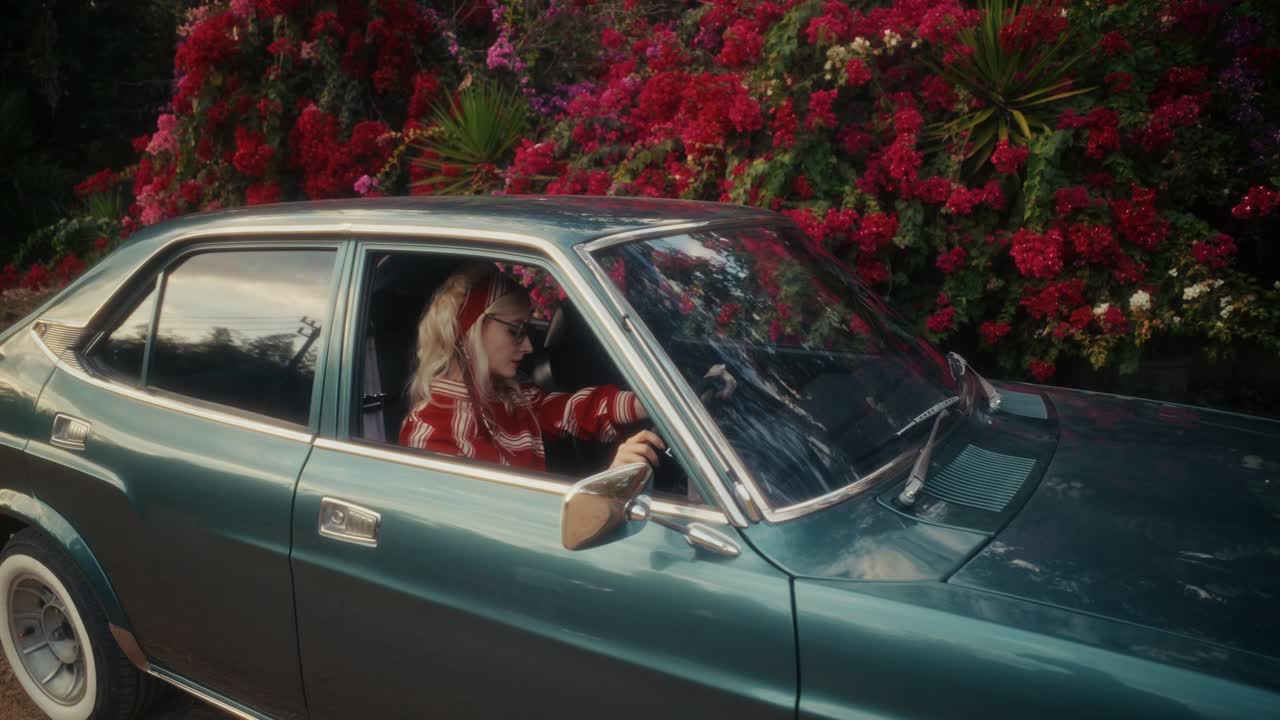 Retro-Frau in Oldtimer neben roter Bougainvillea